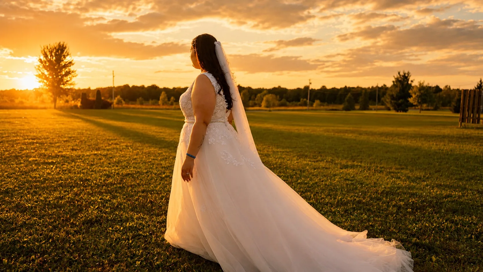 Bride walking through a field at sunset